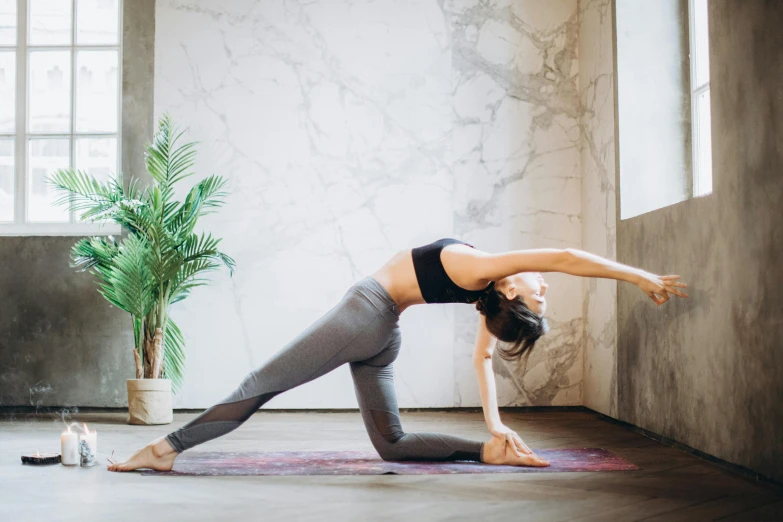 a woman doing a yoga pose in a room, pexels contest winner, arabesque, bending over, background image, long tail, manuka