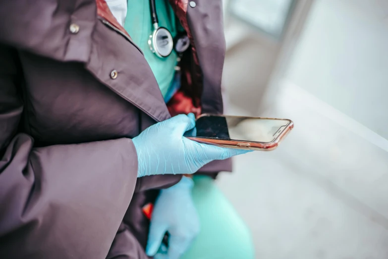 a woman in blue gloves holding a cell phone, healthcare worker, wearing brown robes, instagram photo, digital medical equipment