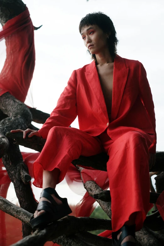 a woman in a red suit sitting on a tree branch, inspired by Vanessa Beecroft, trending on pexels, gutai group, myanmar, androgyny, tailored clothing, on ocean