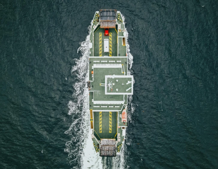 a large boat traveling across a body of water, by Adam Marczyński, pexels contest winner, hurufiyya, head straight down, automated defence platform, symmetrical, a green