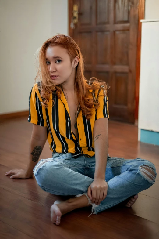 a woman sitting on the floor in a room, a portrait, inspired by Elsa Bleda, trending on pexels, hyperrealism, striped shirt, red gold hair, malaysian, yellow and black