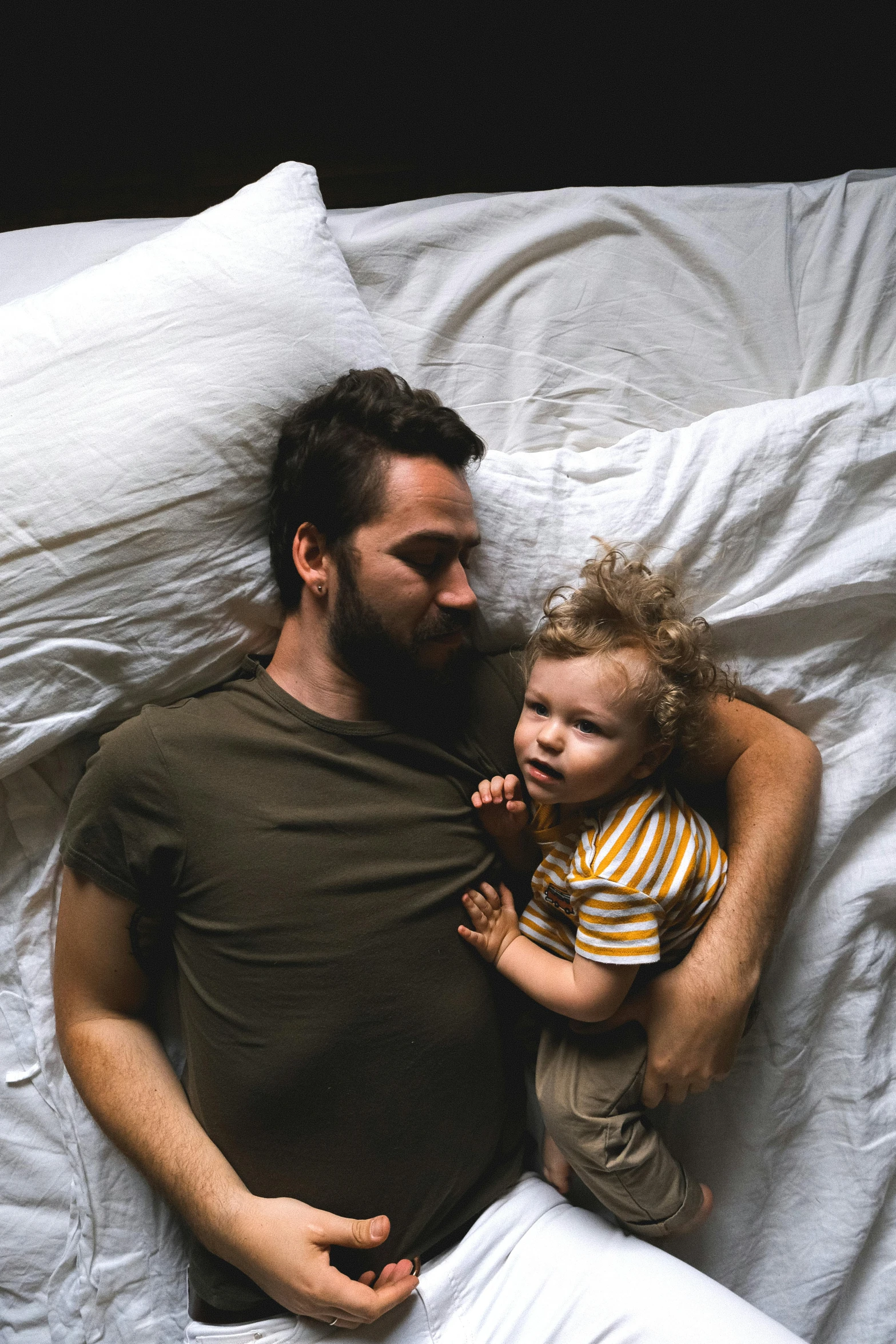 a man laying in bed with a small child, pexels contest winner, symbolism, charlie day, ignant, extremely handsome, lgbtq