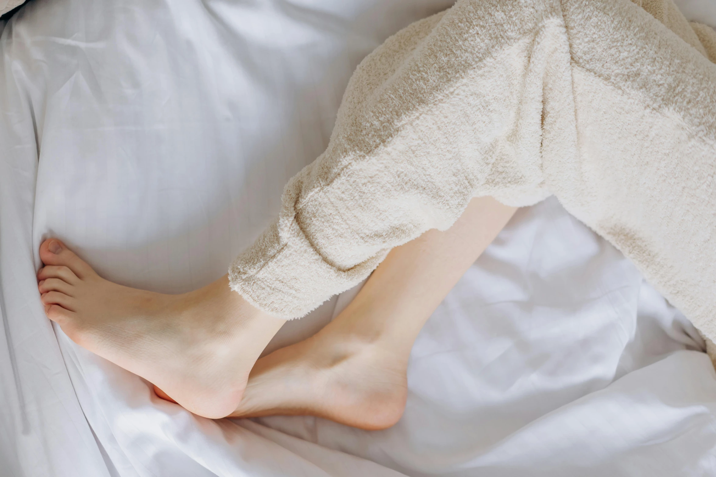 a close up of a person laying on a bed, trending on pexels, bare leg, wearing pajamas, smooth healthy skin, slightly pixelated