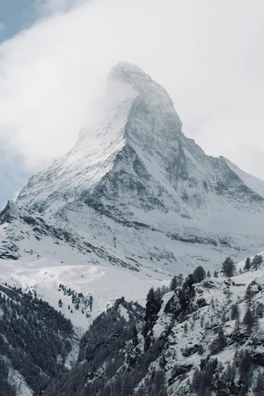 a man riding skis down a snow covered slope, an album cover, by Johannes Voss, pexels contest winner, giant imposing mountain, cone shaped, photo of zurich, seen from a distance