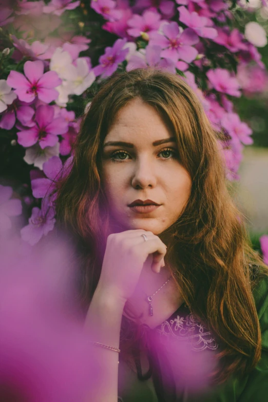 a woman standing in front of purple flowers, inspired by Elsa Bleda, pexels contest winner, portrait of teenage girl, brown haired, center of image, low quality photo