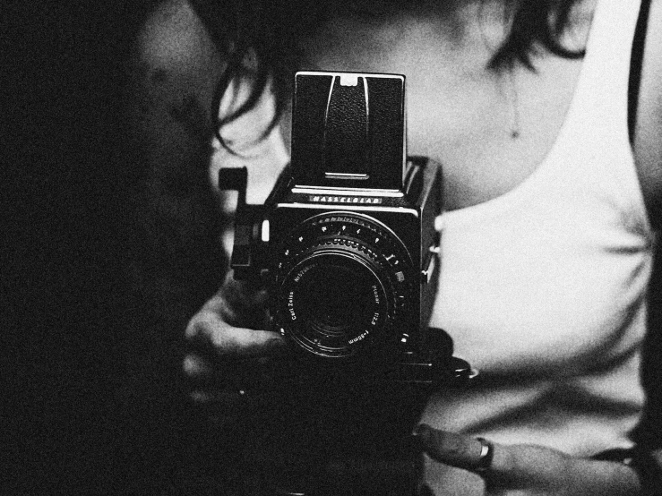 a black and white photo of a woman holding a camera, a black and white photo, unsplash, art photography, digital art #oneshotgame, medium format, grainy vintage, hasselblad photograph