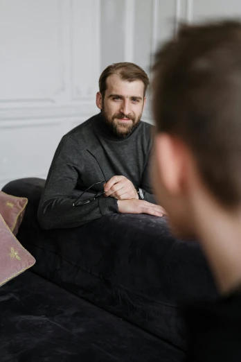 a man sitting on a couch in front of a mirror, smiling at each other, man sitting facing away, lgbtq, leaked photo