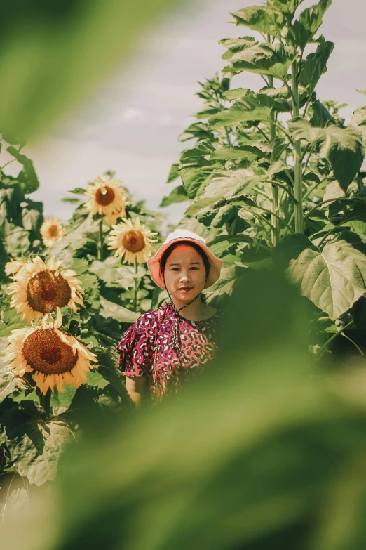 a little girl standing in a field of sunflowers, by Yasushi Sugiyama, unsplash contest winner, ao dai, covered in plants, shot on kodak ektar, taken in the early 2020s