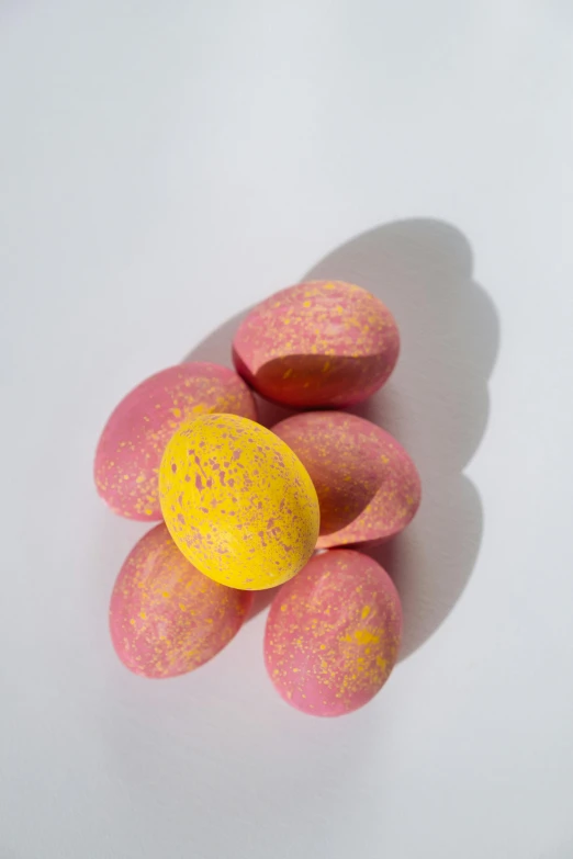 a white plate topped with pink and yellow candies, eggshell color, heavy pigment, smooth matte, speckled