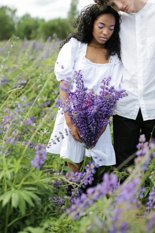 a man and a woman standing in a field of flowers, lavender flowers, with a kid, holding close, loosely cropped