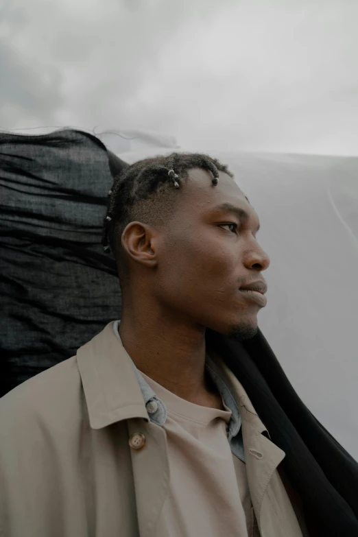 a man standing in front of a pile of luggage, inspired by Barthélemy Menn, trending on unsplash, afrofuturism, sharp cheekbones, grey cloudy skies, 26 year old man on a sailboat, ( ( theatrical ) )