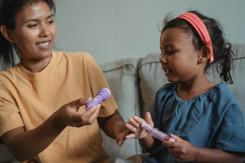 a woman sitting next to a little girl on a couch, pexels contest winner, hurufiyya, purple tubes, tapping in to something greater, the woman holds more toys, manuka