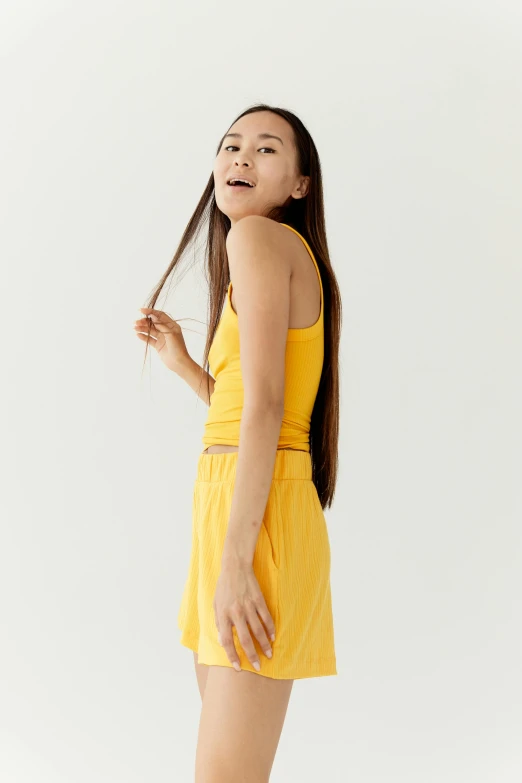 a woman in a yellow dress posing for a picture, wearing a tank top and shorts, gongbi, wearing : tanktop, 1 6 years old
