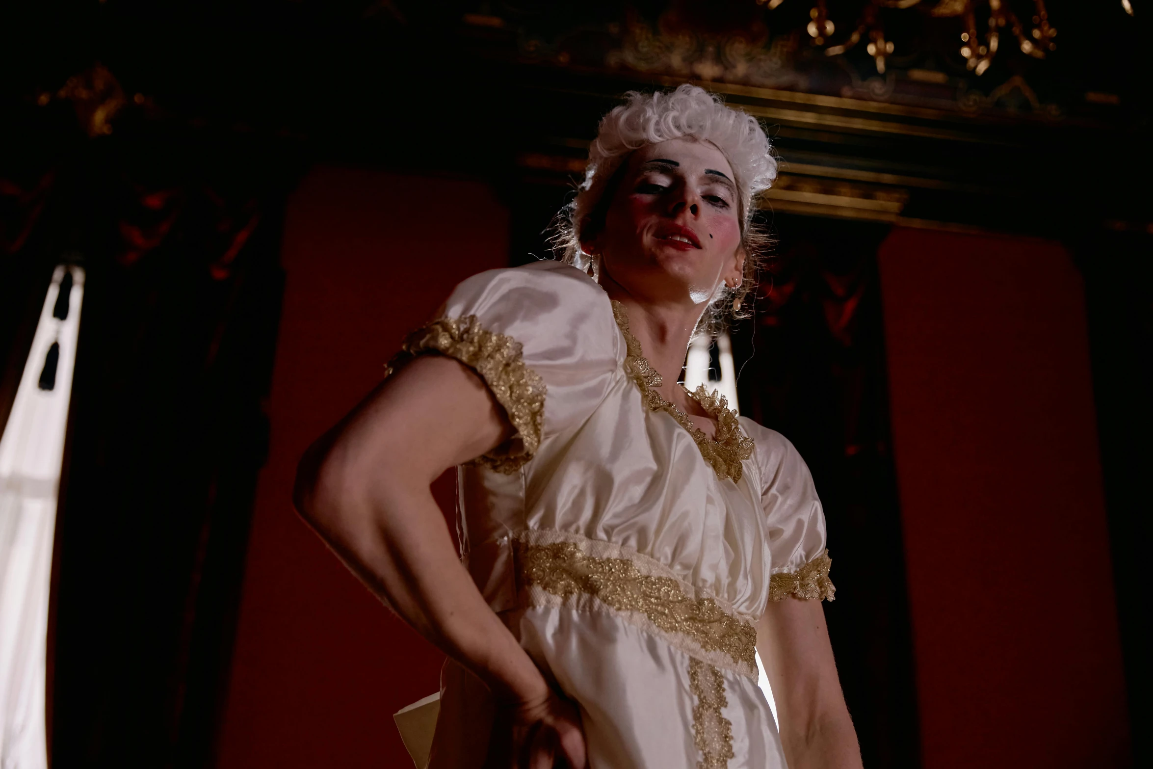 a woman in a white dress standing in a room, inspired by Cindy Sherman, rococo, performance, white facepaint, standing in a dimly lit room, dressed in roman clothes