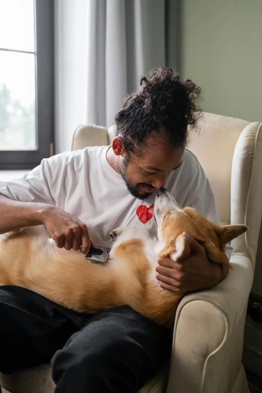 a man sitting in a chair holding a dog, dry brushing, cat and dog licking each other, on a couch, essence