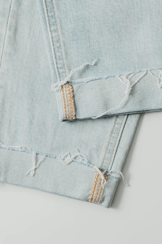 a pair of jeans sitting on top of each other, pale blue, detail shot, high damage, high-body detail