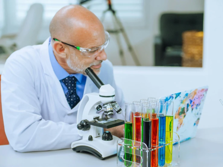 a man in a lab coat looking through a microscope, a colorized photo, pexels contest winner, fan favorite, hide the pain harold, colorful medical equipment, wizard examining eggs