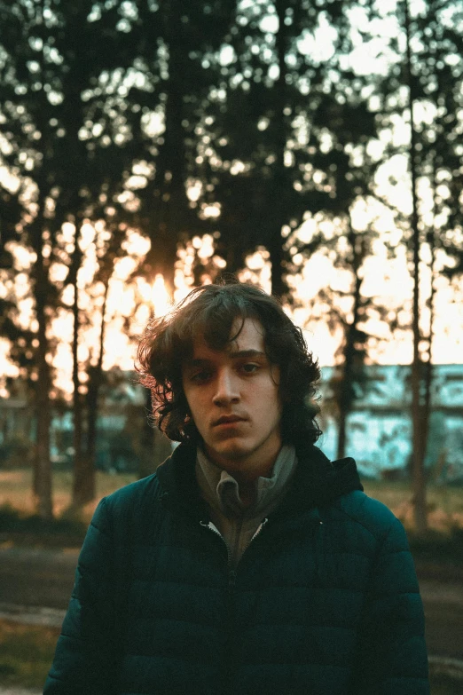 a man standing in the middle of a forest, an album cover, pexels contest winner, portrait of a young italian male, ((sunset)), cinestill 800t 35mm eastmancolor, in a city park