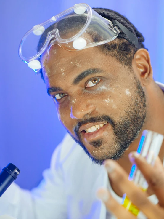 a man in a lab coat and goggles holding a test tube, inspired by Ismail Gulgee, pexels contest winner, beard stubble, oil slick, official screenshot, makeup