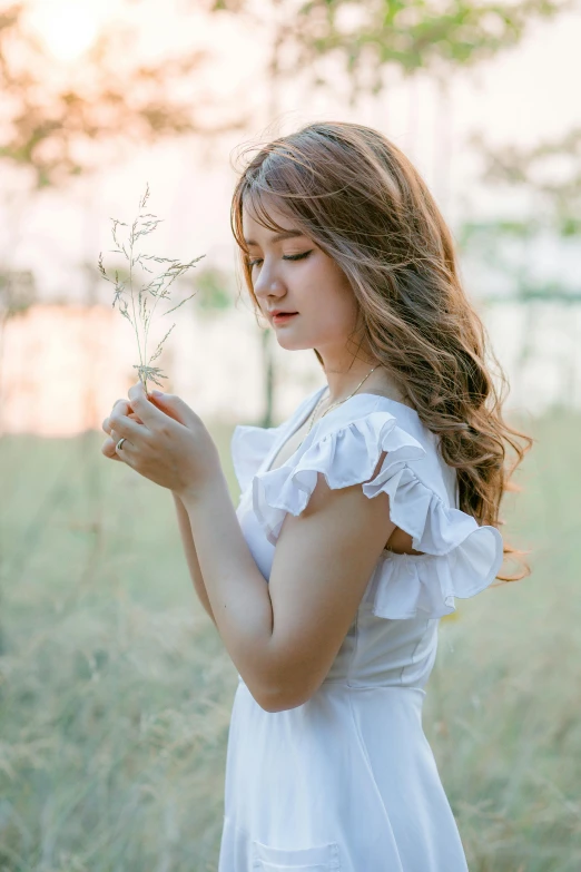 a woman standing in a field holding a flower, inspired by Kim Du-ryang, unsplash, renaissance, wearing white camisole, square, light effect. feminine, teen girl