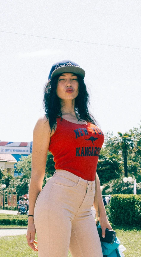 a woman standing in the grass with a skateboard, inspired by Noe Canjura, wearing red tank top, official store photo, los angelos, bib bang