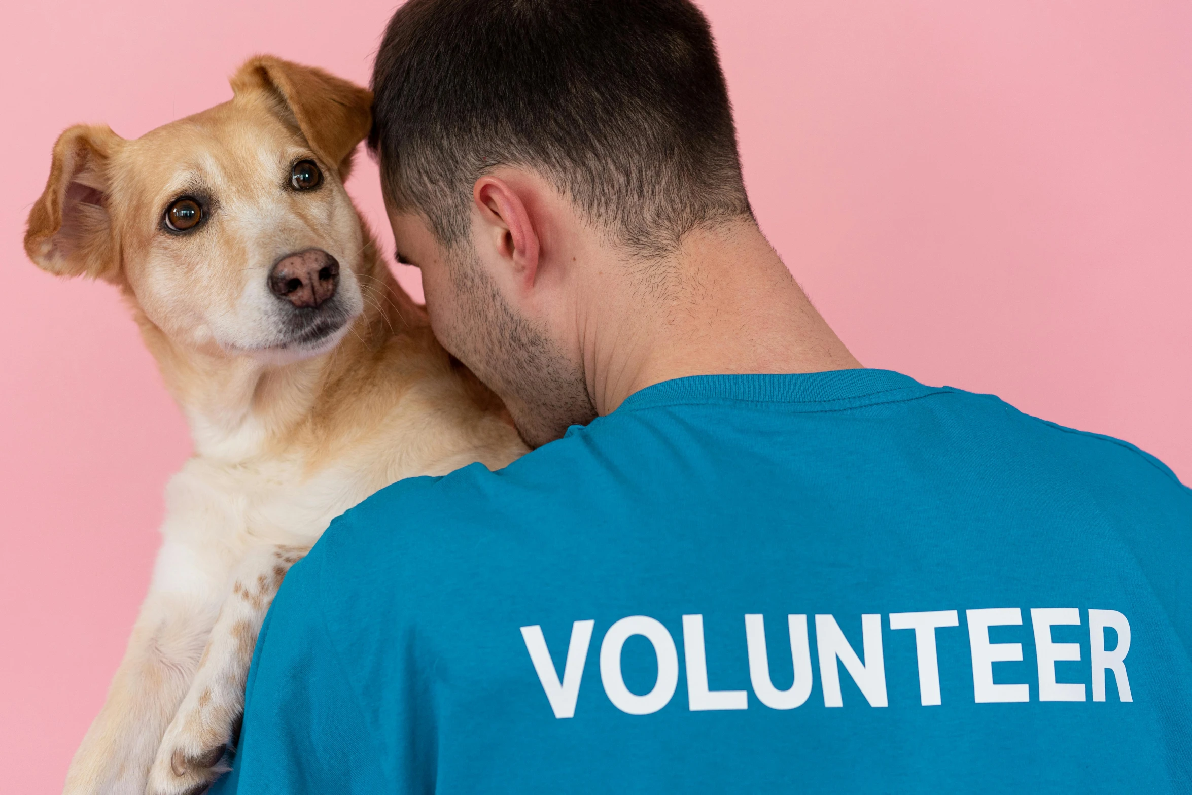 a man holding a dog in his arms, inspired by Elke Vogelsang, shutterstock, renaissance, healthcare worker, pink, in a dark teal polo shirt, sustainability