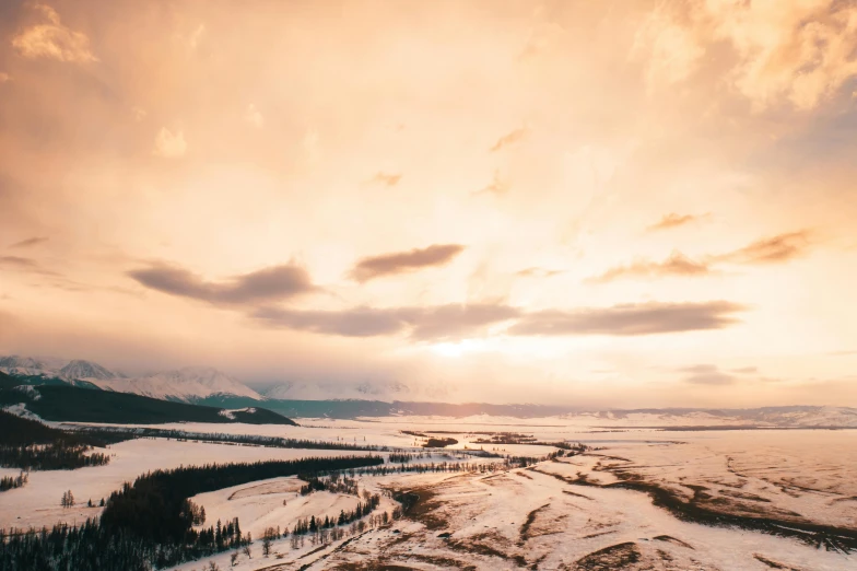 a person riding skis on top of a snow covered slope, by Jessie Algie, unsplash contest winner, hurufiyya, hazy sunset with dramatic clouds, wide river and lake, aerial footage, farming