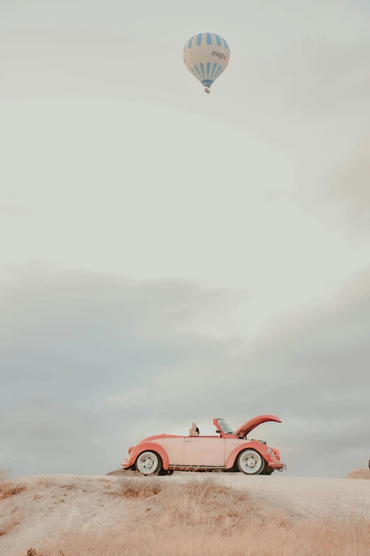 a car and a hot air balloon in the sky, unsplash, pink bees, beetle, minimalist photo, color”