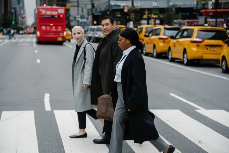 a group of people walking across a street, inspired by Peter Lindbergh, pexels contest winner, mix of ethnicities and genders, trench coat and suit, humans of new york, three women