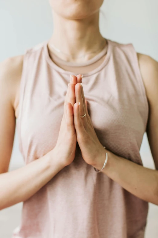 a woman in a pink tank top is doing yoga, by Carey Morris, trending on unsplash, renaissance, prayer hands, thin gold details, wearing cross on robe, curated collections