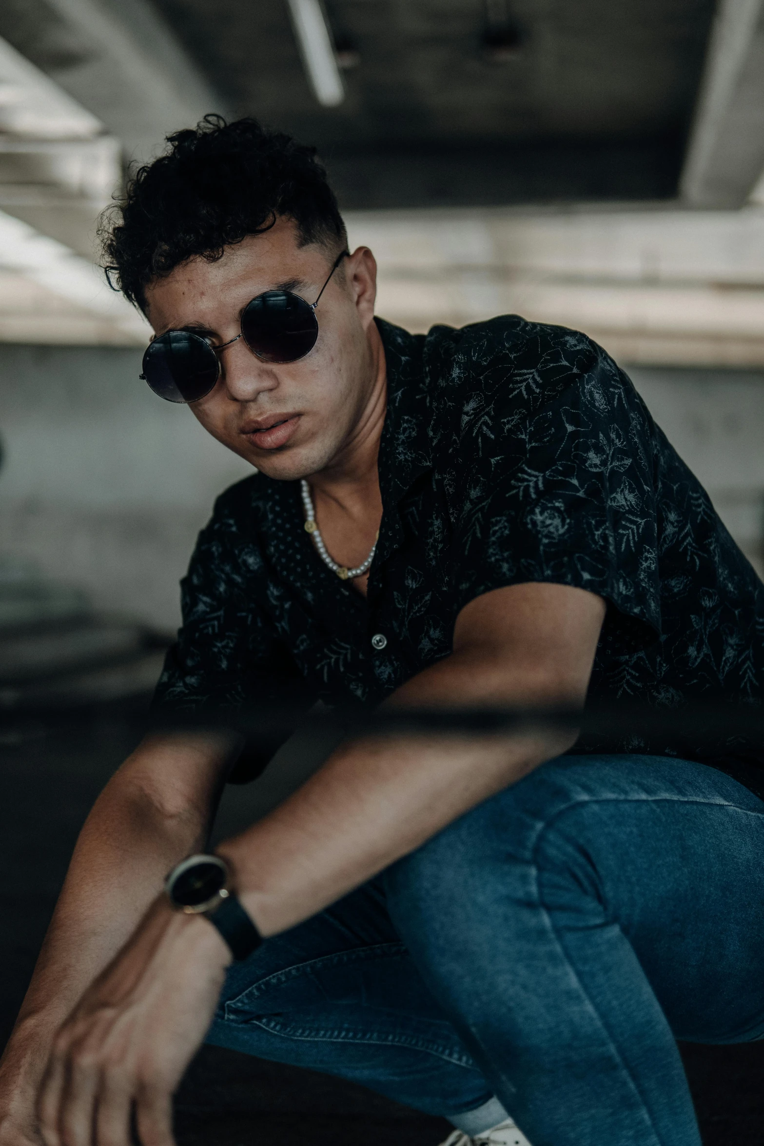 a man sitting on a skateboard in a parking garage, an album cover, inspired by Carlos Berlanga, trending on pexels, black sunglasses, headshot profile picture, male teenager, dark backdrop