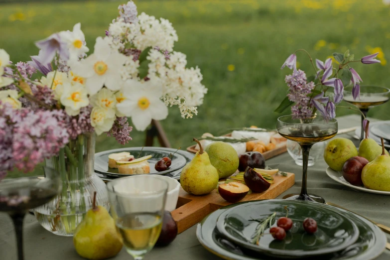 a table topped with plates of food and glasses of wine, inspired by Konstantin Somov, unsplash, fruit and flowers, exterior shot, grey, meadows