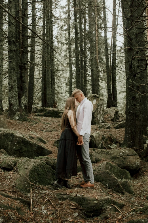 a man and woman standing next to each other in a forest, a picture, by Else Alfelt, pexels contest winner, video footage, standing on rocky ground, kissing, ((forest))