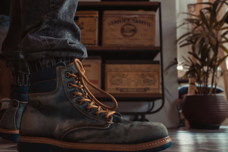 a man standing on top of a wooden floor next to a plant, a colorized photo, pexels contest winner, heavy-duty boots, wearing denim, sitting on a store shelf, detailed close foot shot