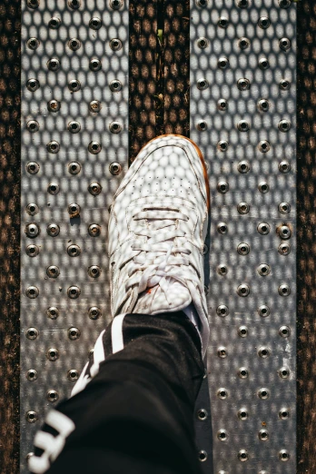 a person standing on top of a metal platform, a picture, by Carey Morris, trending on unsplash, patterned, sneaker photo, in an elevator, white with black spots