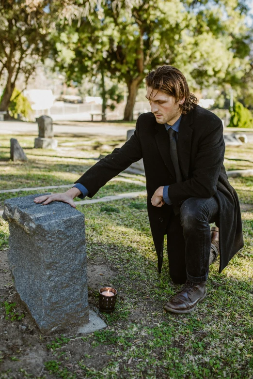 a man kneeling down next to a grave, a portrait, unsplash, tommy wiseau, bo burnham, elegantly dressed, profile image