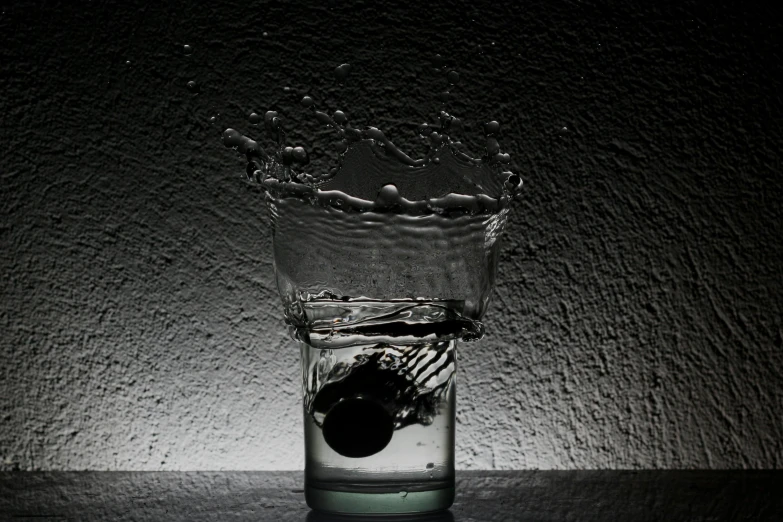 a glass of water with a black object in it, inspired by Robert Mapplethorpe, splashing, lights, waterfals, splash image