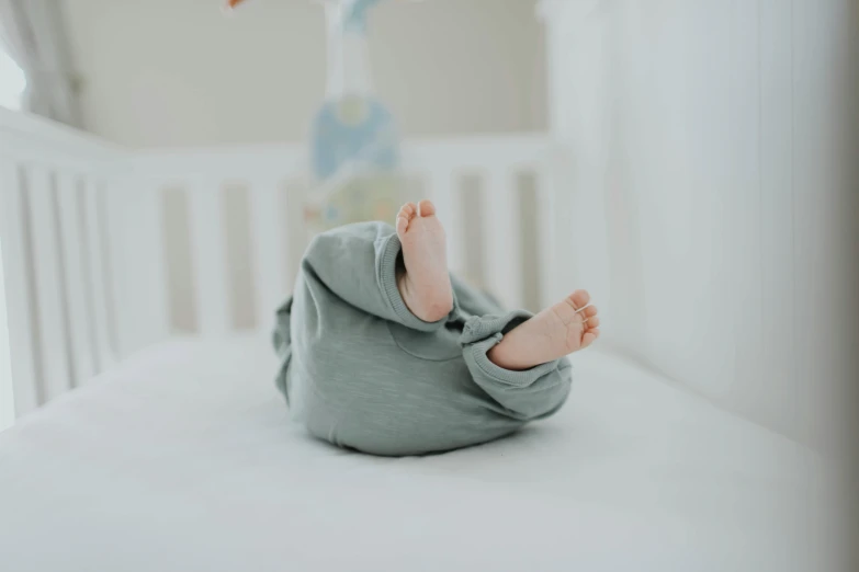 a close up of a baby's feet in a crib, pexels contest winner, arabesque, grey clothes, muted green, full body hero, laying on their back