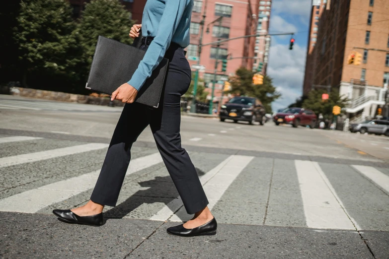 a woman walking across a street holding a briefcase, inspired by Garry Winogrand, arabesque, black loafers, thumbnail, dynamic angled shot, innovation