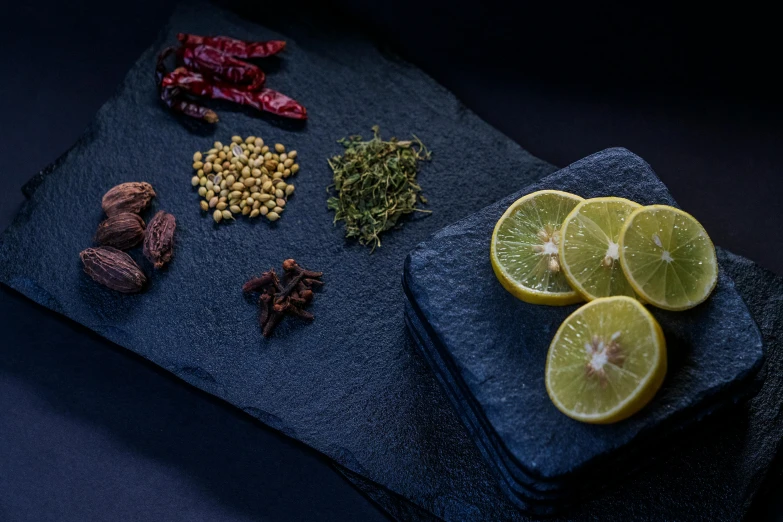 a cutting board topped with sliced lemons and spices, by Kristian Zahrtmann, pexels contest winner, slate, moonlit, drink, dried herbs