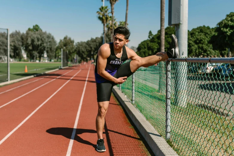 a man leaning on a fence on a track, purple bridges with leggins, posing and flexing, david marquez, profile image