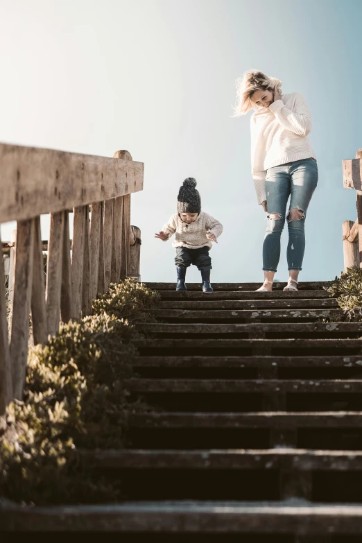 a woman and a child walking up a flight of stairs, pexels contest winner, rising up from ocean, denim, walking on an old wood bridge, kids playing