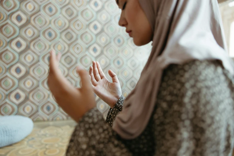 a woman in a hijab is praying, a picture, inspired by Modest Urgell, shutterstock, hurufiyya, partially cupping her hands, delicate patterned, waving, malaysian