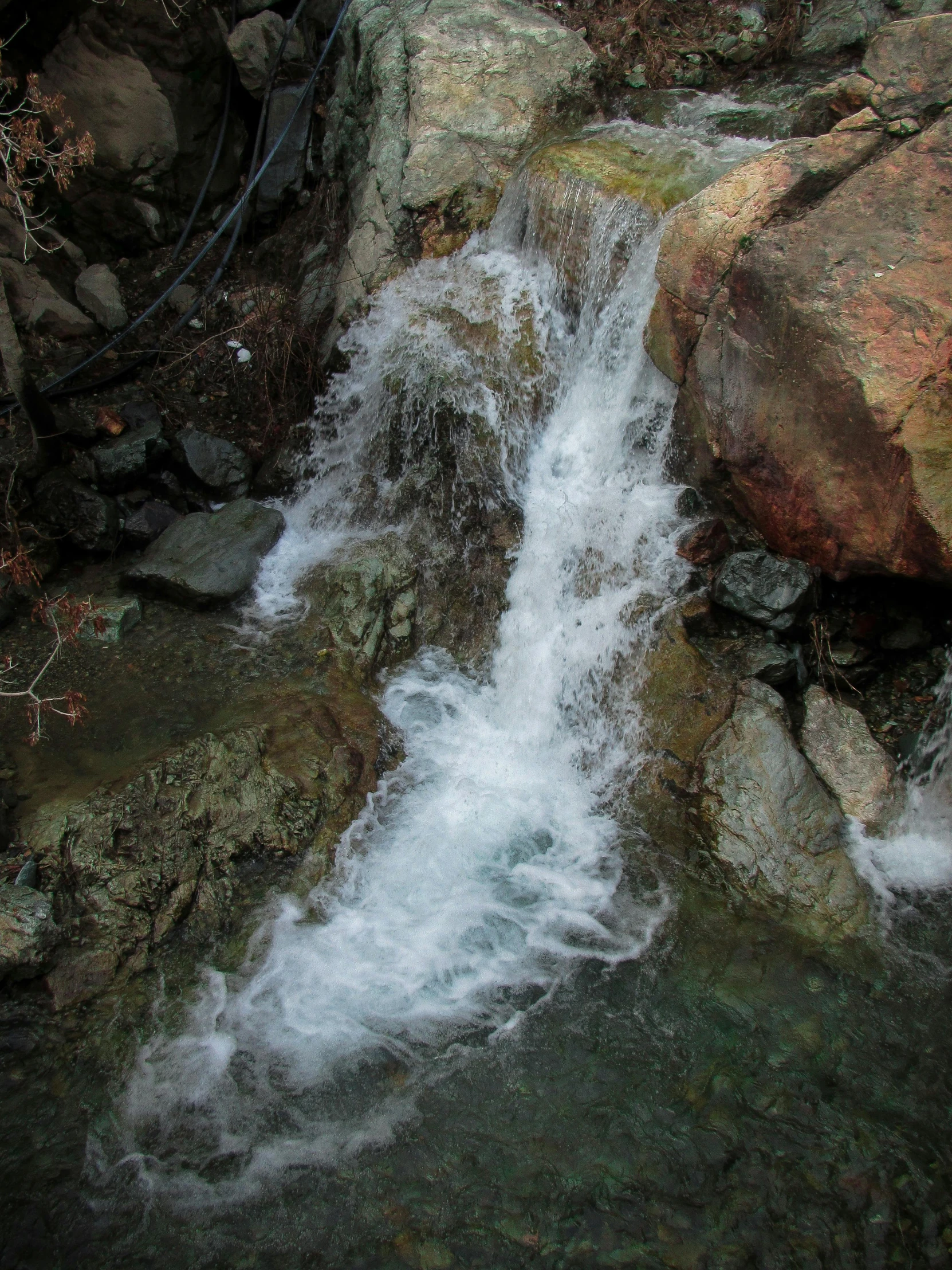 a stream running through a lush green forest, an album cover, unsplash, hurufiyya, rocky terrain, low quality photo, frozen waterfall, malibu canyon