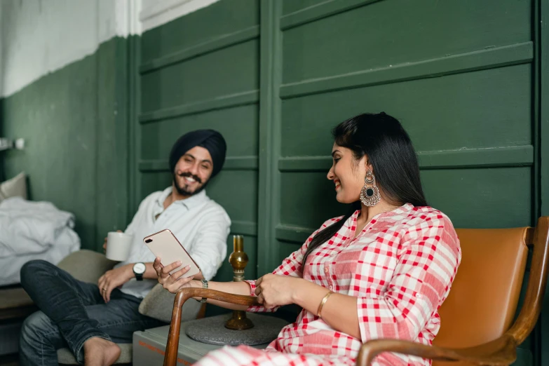 a man and a woman sitting next to each other, by Manjit Bawa, pexels contest winner, sitting in a lounge, promotional image, cheerful atmosphere, looking around a corner