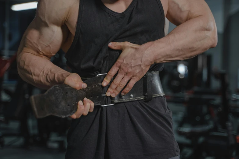 a man holding a hammer in a gym, pexels contest winner, wearing an ammo belt, wearing a tanktop, potion belt, lachlan bailey