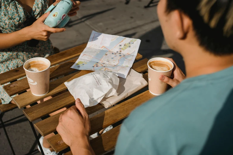 a couple of people sitting at a table with cups of coffee, open street maps, 🚿🗝📝, paper cup, ryan jia