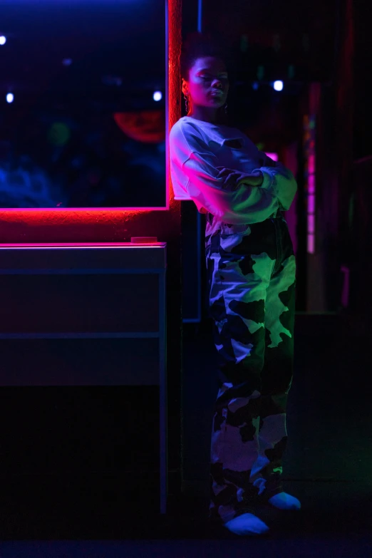 a person standing in front of a neon sign, inspired by Elsa Bleda, holography, stage at a club, looking out, colourful clothing, high-contrast lighting