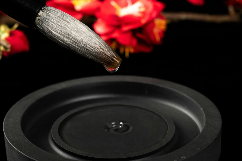 a close up of a brush with a flower in the background, inspired by Gong Kai, shutterstock contest winner, metal lid, pouring techniques, made of smooth black goo, hasselblad quality
