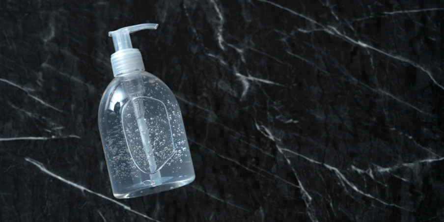 a bottle of hand sanitizer sitting on a marble counter, by Matija Jama, shutterstock, plasticien, carved black marble, tansparent water, silicone skin, soap bubbles